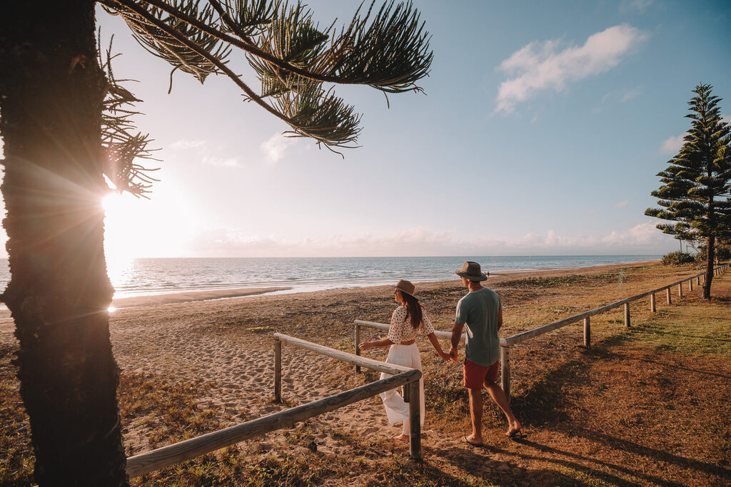Couple standing on Forrest Beach at sunset | Tasman Holiday Parks
