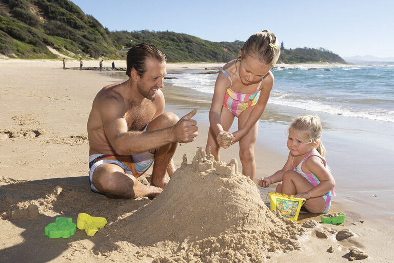 Kids and father building sandcastle on the beach | Tasman Holiday Parks