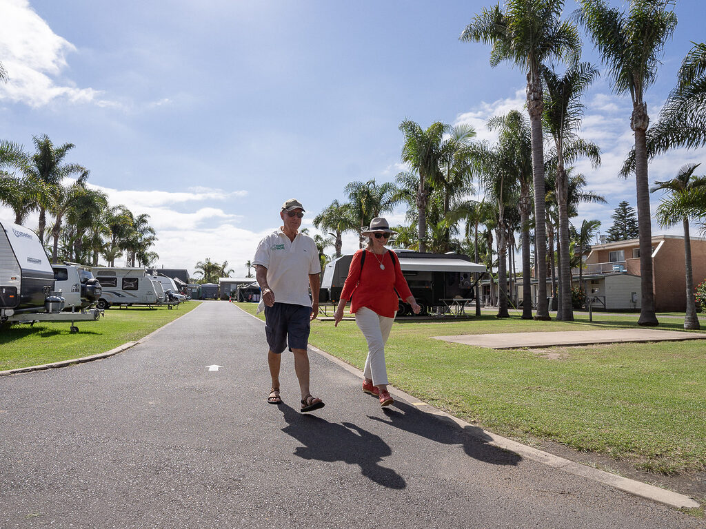 Mature couple walking through Tasman Holiday Parks Tathra Beach