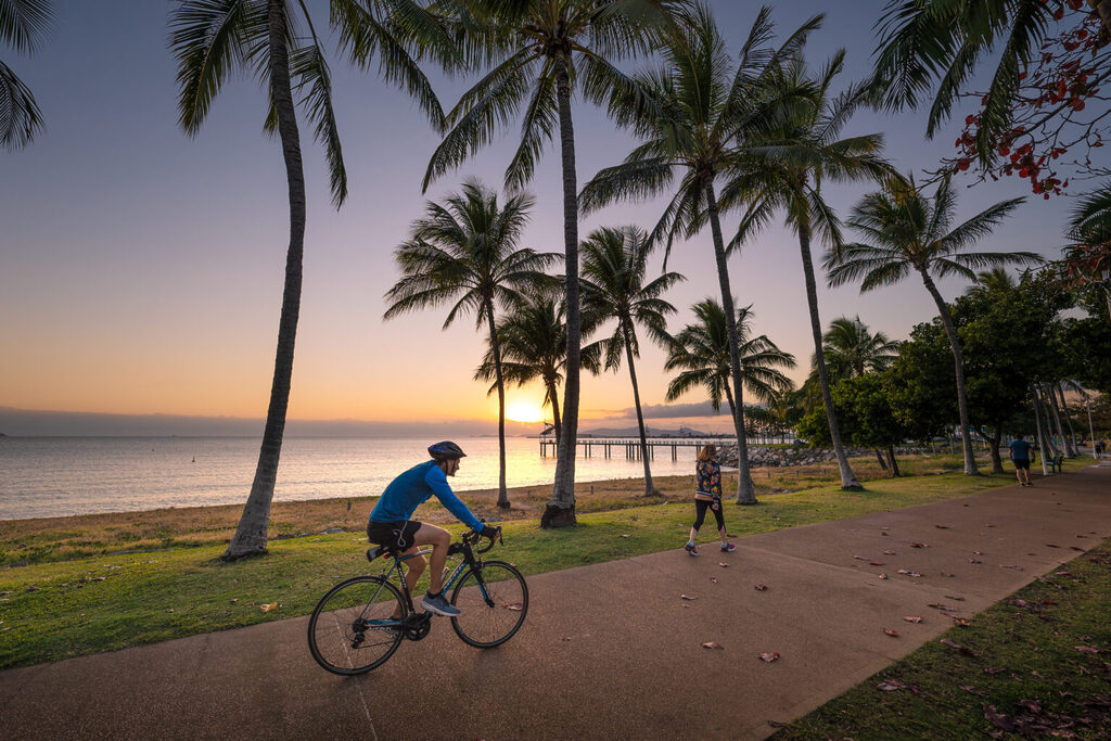 Townsville beachfront man riding a bike at sunset | Tasman Holiday Parks Rowes Bay