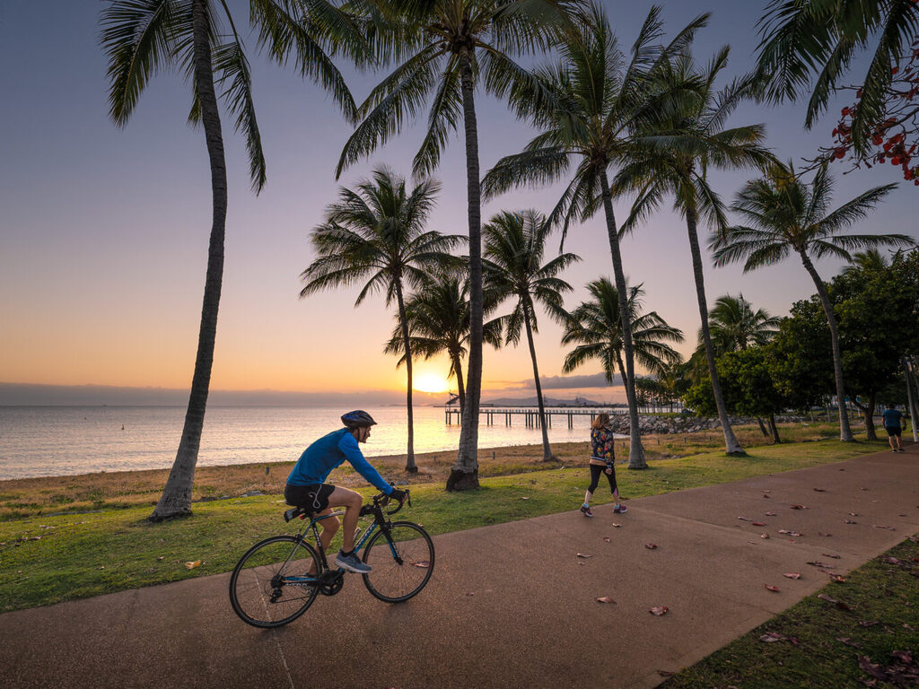 Townsville beachfront man riding a bike at sunset | Tasman Holiday Parks Rowes Bay