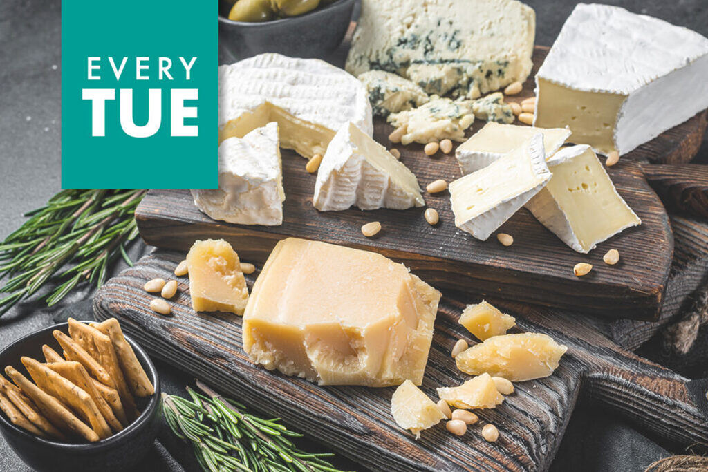 A variety of cheeses including brie, blue cheese, and aged cheddar are displayed on wooden boards. The cheeses are garnished with pine nuts and sprigs of rosemary. A bowl of crackers is on the side. Text in the top left corner reads "Every Tue.