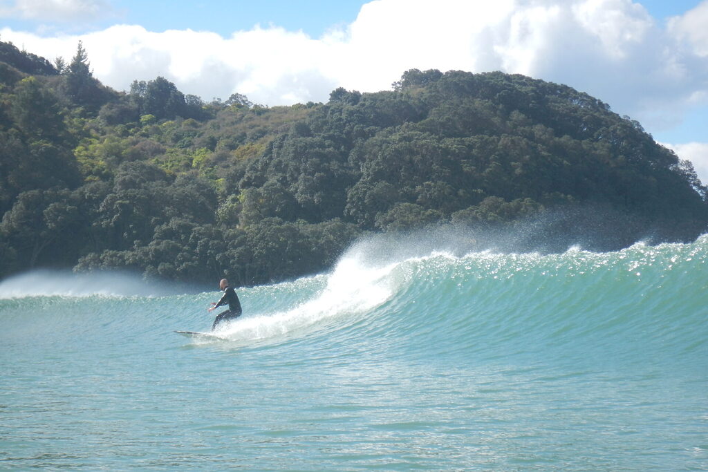 Surfer catching a wave at waihi beach