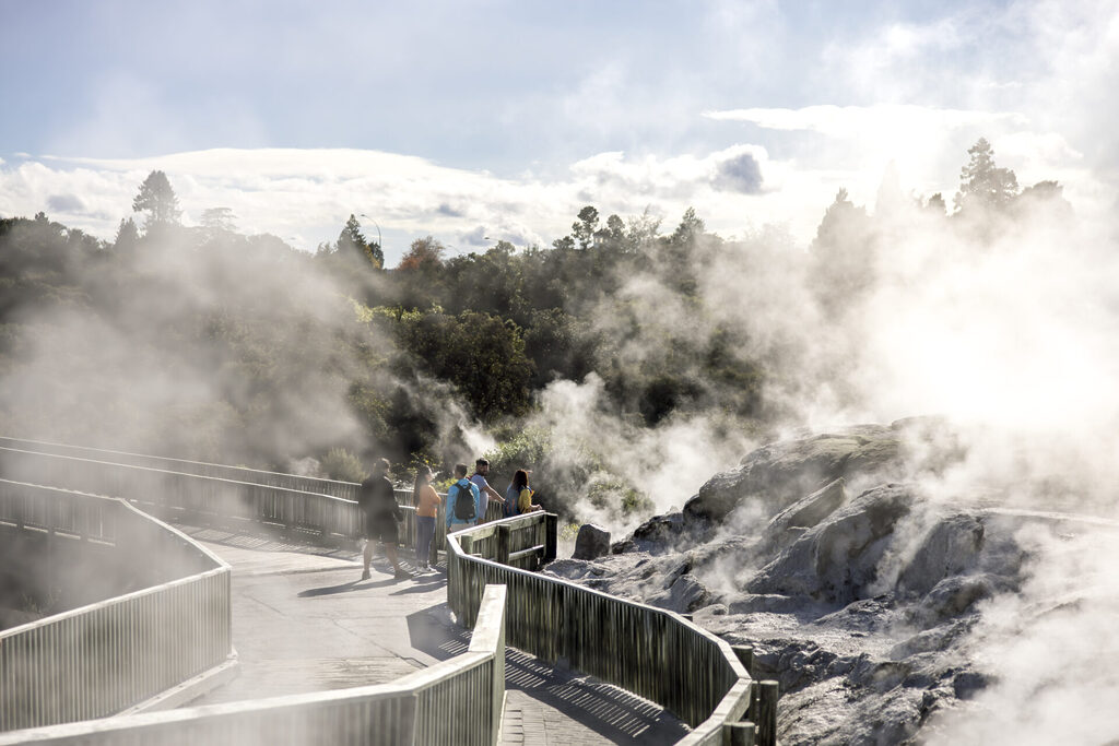 visitors walking along the boardwalk through Te Puia thermal area in Rotorua