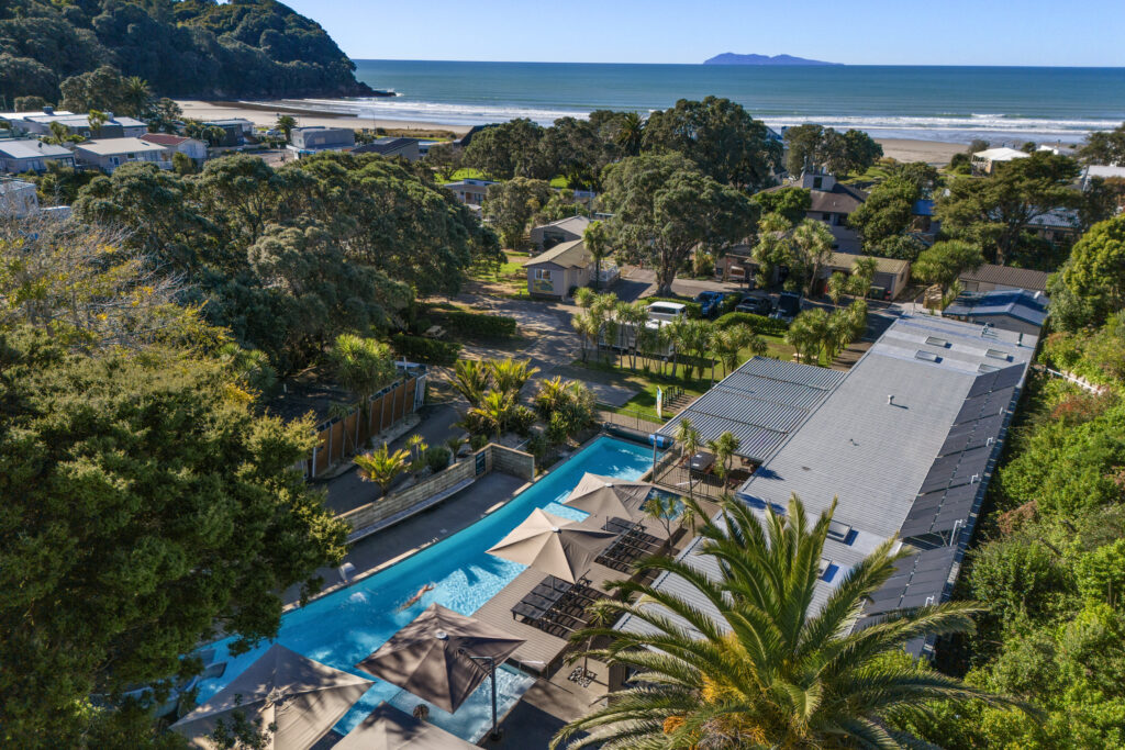 Aerial of Tasman Holiday Parks Waihi Beach showing pool, beach and ocean