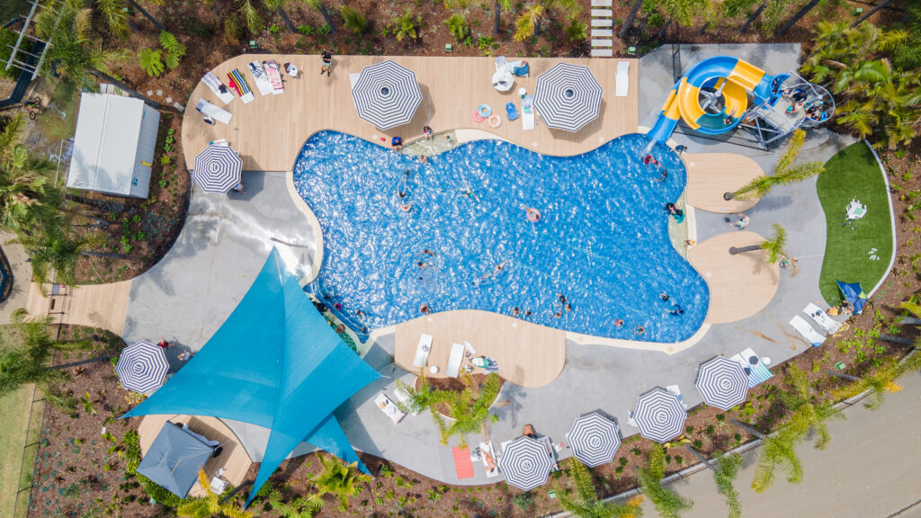 Aerial view of a vibrant outdoor swimming pool with waterslides. 