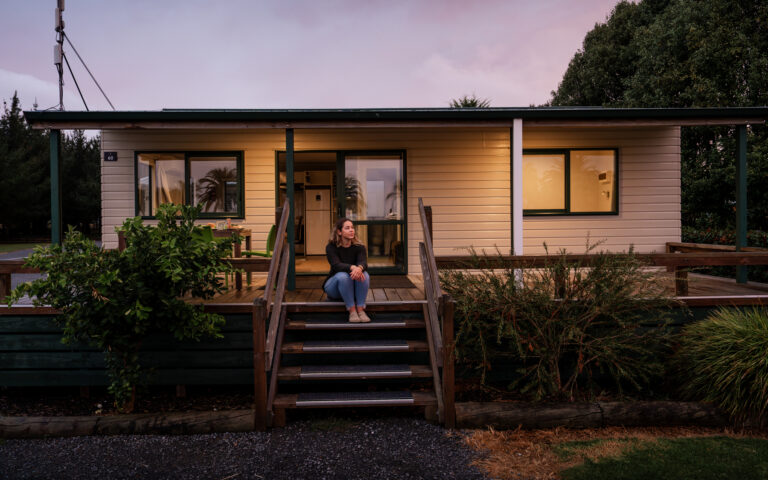 A woman sits on the front steps of a cabin